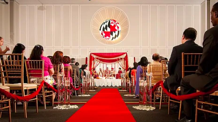Ceremony with red carpet leading to stage with couple