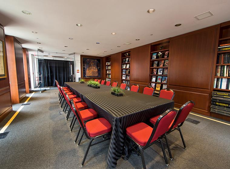 Library set with long rectangular tables covered in black striped linen and surrounded by red/black chair