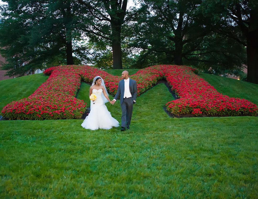 Bride and groom by floral "M" in gardens