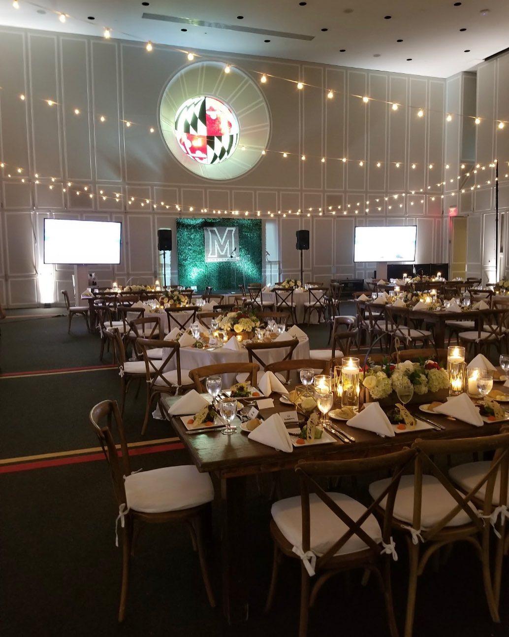 Rustic style event with hanging lights and long tables with brown chivari chairs