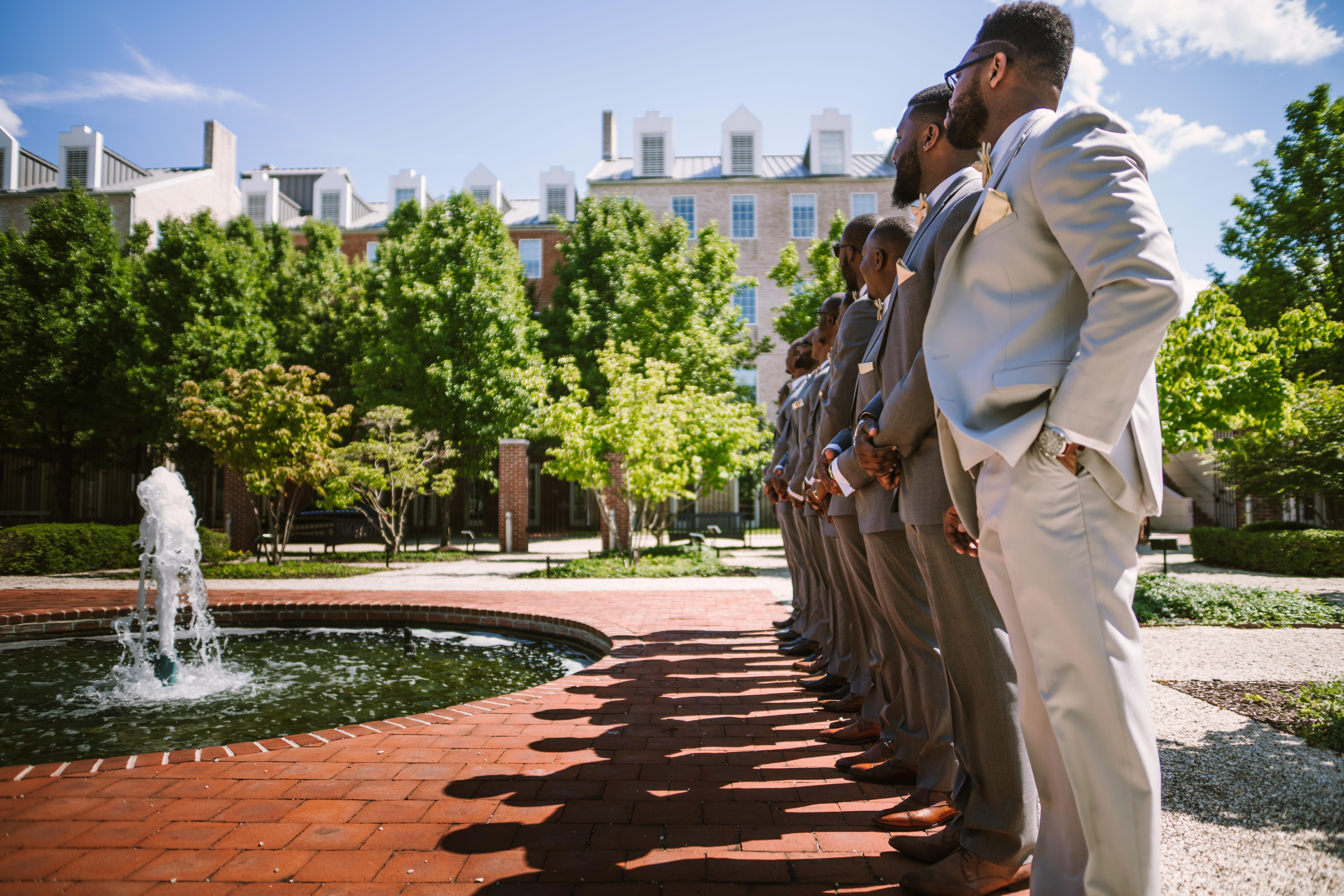 Groomsmen lining fountain in garden